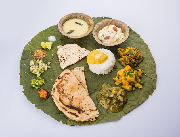 Tipico piatto di cibo maharashtrian sano o Thali pieno di sostanze nutritive servito su piatto costituito da foglie verdi degradabili, messa a fuoco selettiva