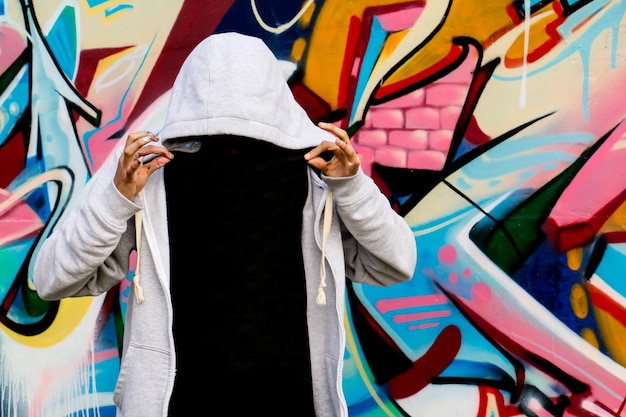Tipo urbano giovane artista di graffiti di modello che mostra i vestiti per mettere la pubblicità