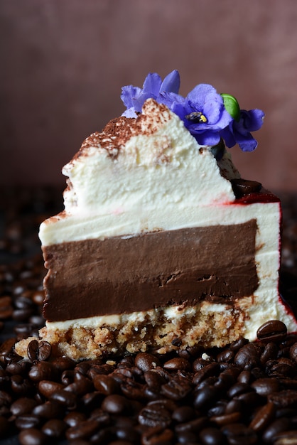 Tiramisù alla torta con glassa al cioccolato con crema al mascarpone e decorato con chicchi di caffè e viole