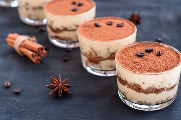 Tiramisù in un bicchiere decorato con chicchi di caffè su uno sfondo scuro