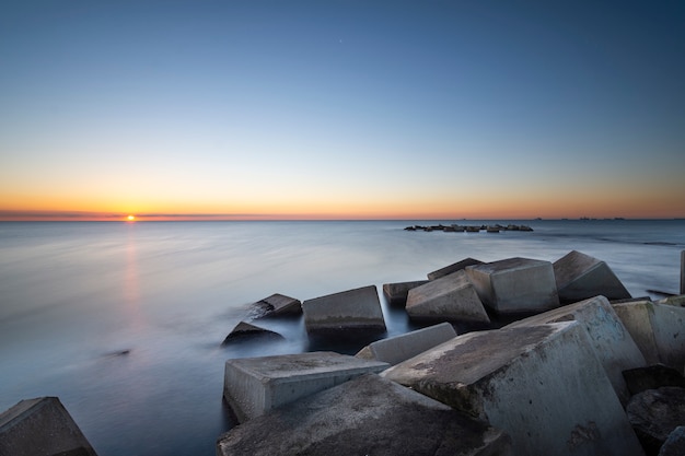 Tiri il fondo in secco all&#39;alba con le rocce da un frangiflutti