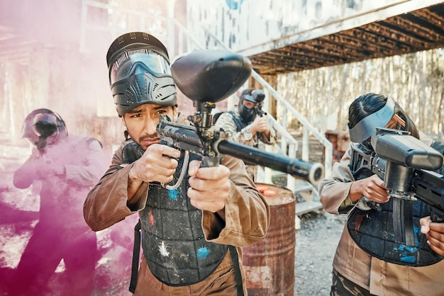 Tiro al lavoro di squadra e paintball con l'uomo in gioco per la guerra e il gioco del parco giochi Sfida la missione e il soldato con persone e fumo nell'arena del campo di battaglia per l'addestramento di pistole e guerrieri