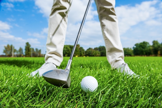 Tiro fuori. Primo piano del giocatore di golf maschio che si stacca mentre si sta in piedi sul campo da golf