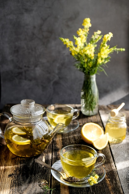 Tisana al limone e miele in tazza di vetro e teiera