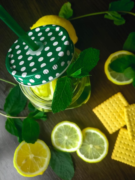 Tisana alla menta in tazza di vetro con limone su fondo di legno