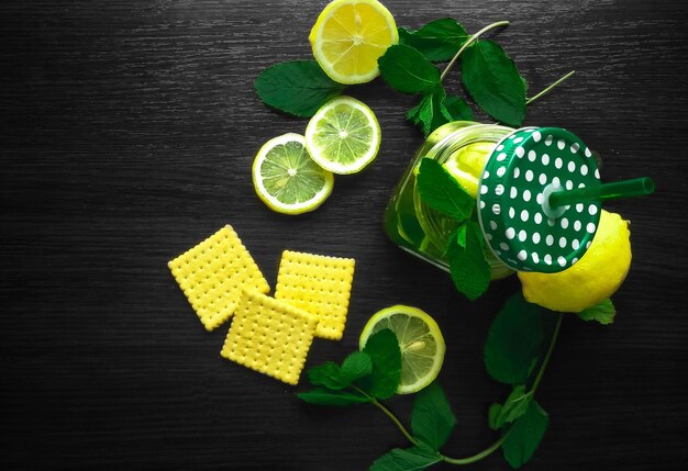 Tisana alla menta in tazza di vetro con limone su fondo di legno