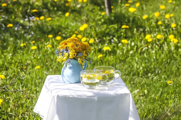 Tisana in una tazza di vetro Fiori di tarassaco in brocca di ceramica