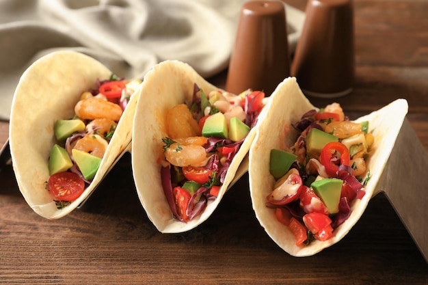 Titolare con deliziosi tacos di gamberetti su tavola di legno