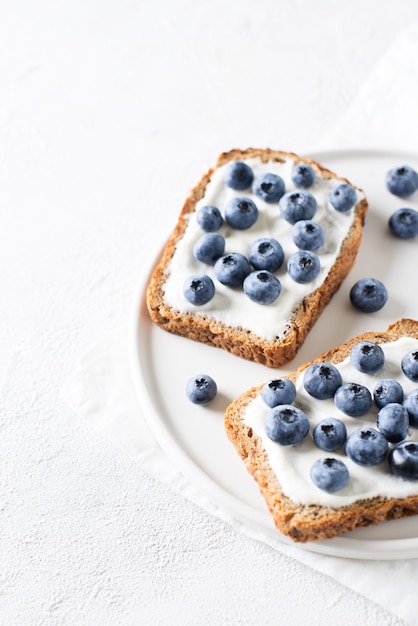 Toast ai mirtilli a colazione su sfondo bianco. Cibo salutare