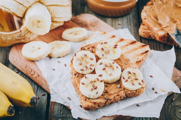 Toast al burro di arachidi con fette di banana su fondo in legno Toast per la colazione