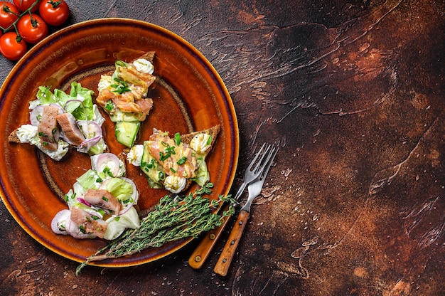 Toast aperto con salmone e aringhe, crema di formaggio e insalata