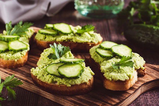 Toast appetitosi con cetrioli guacamole ed erbe aromatiche su una tavola di legno