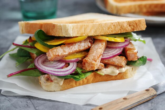 Toast appetitoso con pezzi di pollo e insalata sul tavolo.