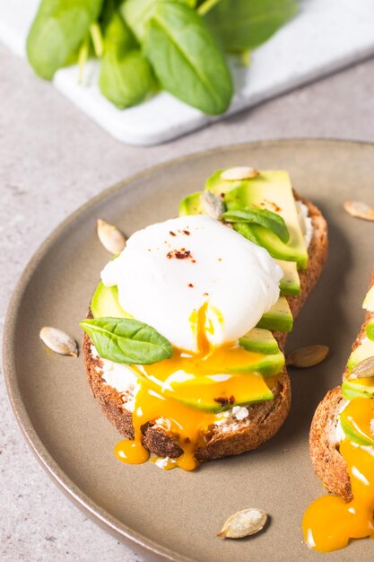 Toast con avocado, crema di formaggio morbido, pane di segale e uovo in camicia.