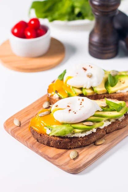 Toast con avocado, crema di formaggio morbido, pane di segale e uovo in camicia.