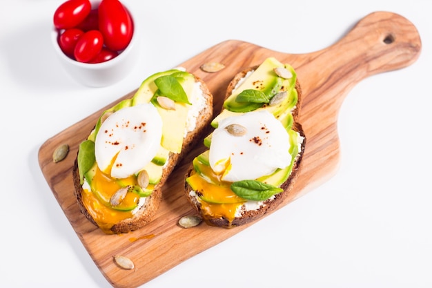 Toast con avocado, crema di formaggio morbido, pane di segale e uovo in camicia.