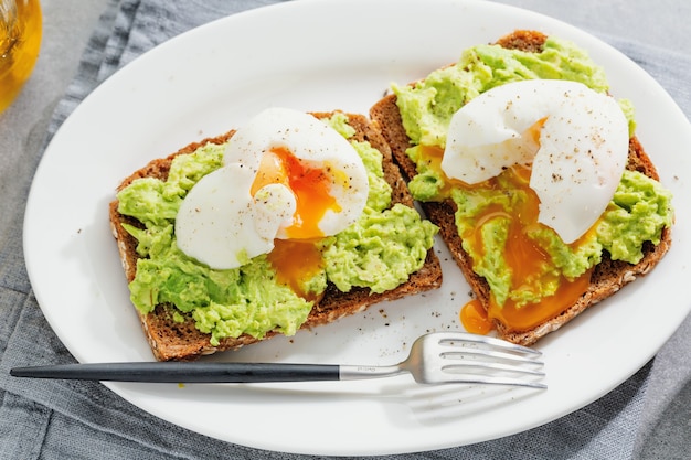 Toast con avocado e uova servite sul piatto. Avvicinamento.