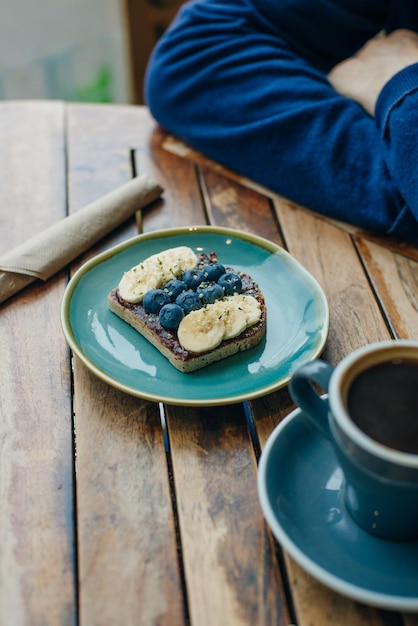 Toast con banane e mirtilli in pasta di cioccolato sul piatto blu