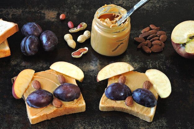 Toast con burro di arachidi a forma di facce di animali. Divertenti tocchi di faccia di animali con burro di arachidi, noci e frutta.