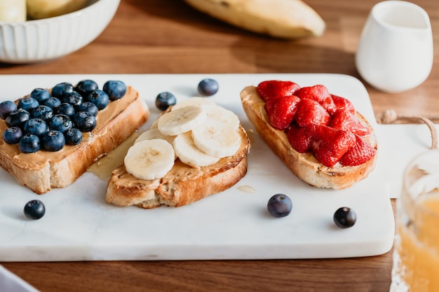 Toast con burro di arachidi mirtillo fragola e banana Concetto di colazione sana