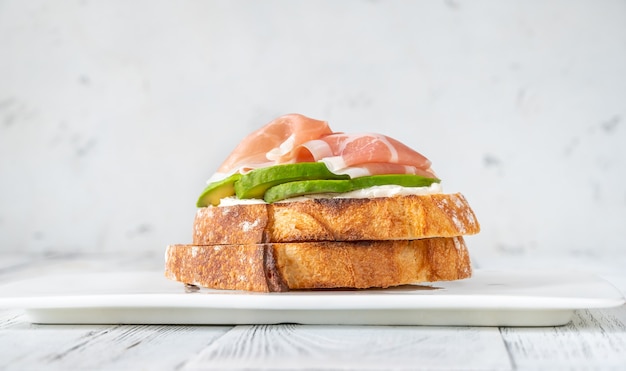 Toast con fette di avocado, prosciutto e crema di formaggio