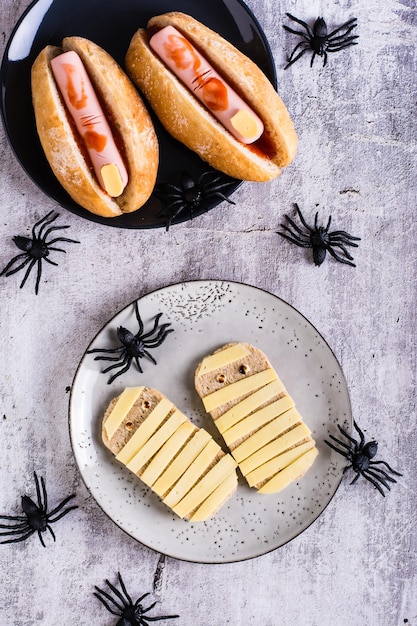 Toast con formaggio a forma di mummie su un piatto e ragni Ricetta di Halloween Superiore e verticale