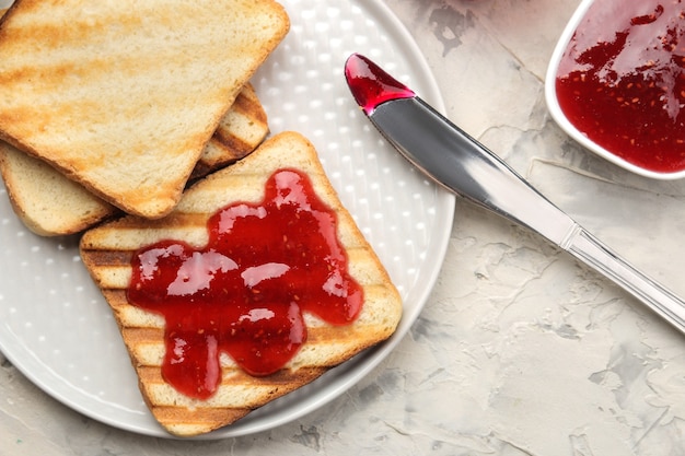 Toast con marmellata. croccanti fritti con marmellata rossa su un tavolo di cemento chiaro. prima colazione. vista dall'alto