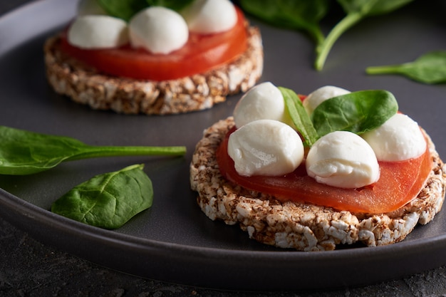 Toast con mozzarella, pomodori e spinaci in un piatto grigio