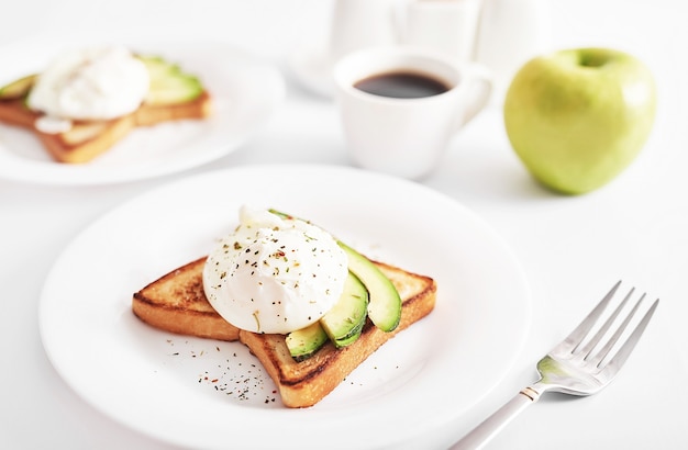 Toast con uova in camicia e avocado. Sana colazione e cibo. Mattina accogliente. Nutrizione per la gravidanza. Dieta per le donne. Colazione in camera o letto d'albergo. Panino con uova strapazzate.