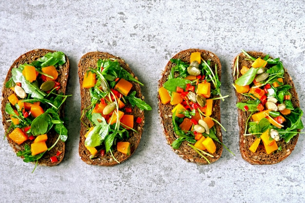 Toast con zucca e rucola. Panini aperti con zucca. Toast vegani sani con verdure e zucca. Merenda autunnale. Bruschetta con rucola e zucca.