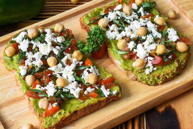 Toast di avocado classico vegetariano con formaggio tofu al pomodoro su tavola di legno