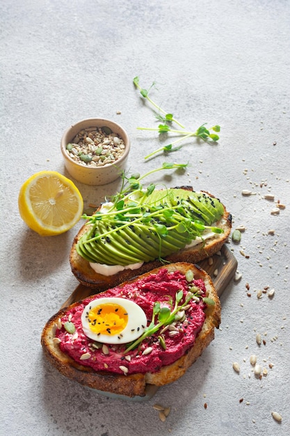 Toast di grano intero con formaggio crema avocado barbabietole hummus semi uova e microgreens