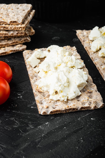 Toast di pane croccante fatto in casa con set di ricotta, sul tavolo di pietra scura nera