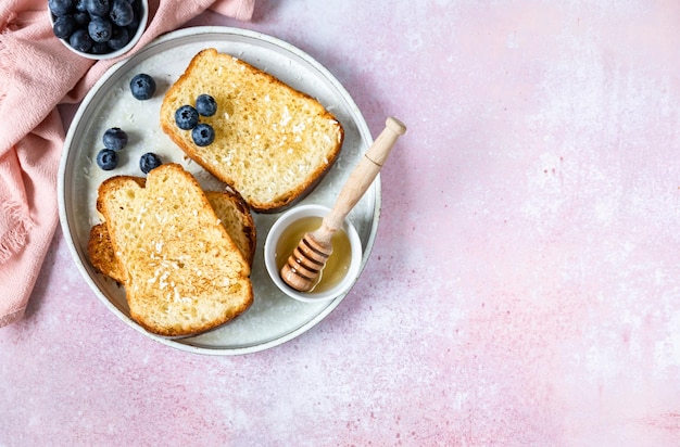 Toast francese condito con miele e scaglie di cocco e mirtillo Concetto di colazione