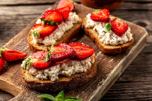 Toast o bruschette con fragole e menta su crema di formaggio ricotta Deliziosa colazione o spuntino vista dall'alto