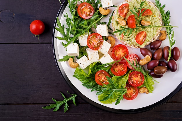 Toast sani di avocado per colazione, guacamole, olive kalamata, pomodori, anacardi e formaggio feta