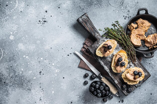 Toast with Foie gras pate and fresh blueberry on wooden board. Gray background. Top view. Copy space.