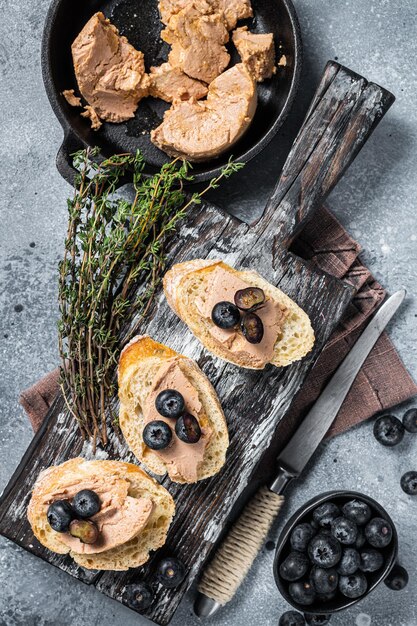 Toast with Foie gras pate and fresh blueberry on wooden board Gray background Top view