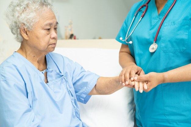 toccando una paziente asiatica anziana con amore cura aiutando a incoraggiare ed empatia in ospedale