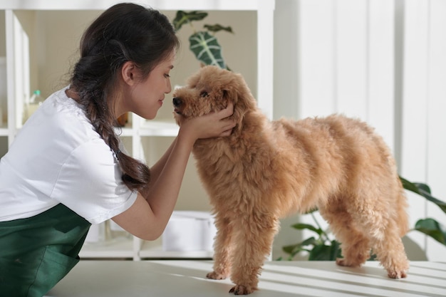 Toelettatore che bacia un cane di piccola taglia