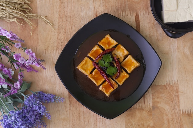 Tofu fritto in piatto nero su fondo di legno