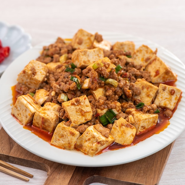 Tofu saltato in padella tradizionale cinese con salsa piccante calda sulla tavola di legno