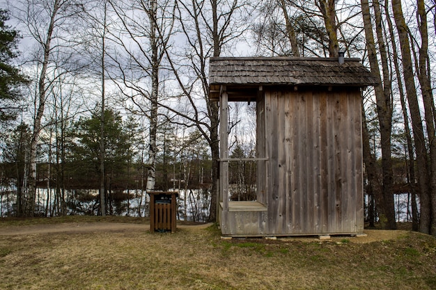 Toilette in legno in natura, vicino agli alberi e a un lago.