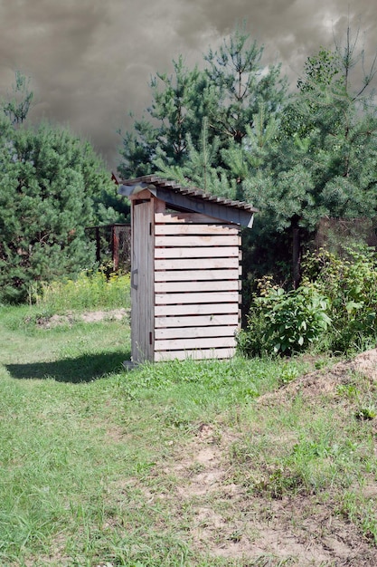 Toilette vintage Una toilette verde rustica all'aperto con un cuore ritagliato sulla porta Toilette in un campo di fiori