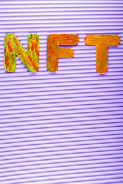 Token non fungibile. Iscrizione NFT di lettere multicolori su sfondo viola. Concetto di arte crittografica