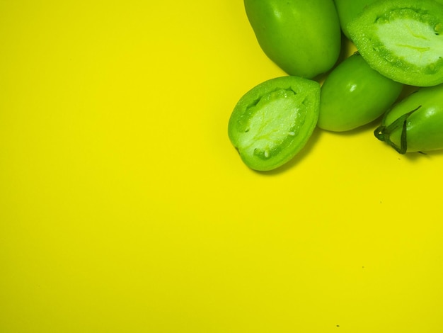 Tomati verdi su uno sfondo giallo Il concetto di una verdura immatura Sfondio di verdure verdi Prodotto di salatura Luogo per scrivere testo