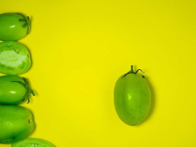 Tomati verdi su uno sfondo giallo Il concetto di una verdura immatura Sottofondo di verdure verdi Prodotto salato Alimento sano Luogo per scrivere testo Tomati dita della signora