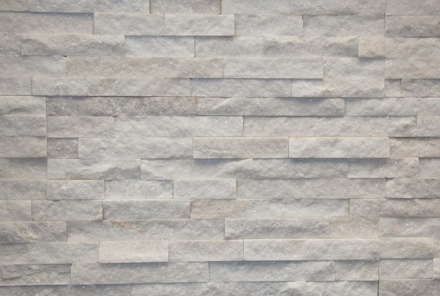 Toni grigi del muro di pietra della parete bianca di superficie per l'uso come sfondo. Mosaico di pietra.