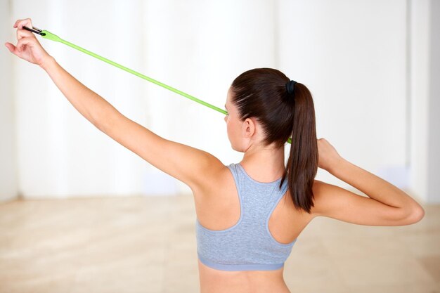 Tonificazione con resistenza Una bella giovane donna che fa allenamento di resistenza in palestra