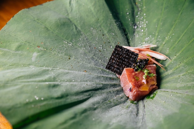 Tonno con salsa yuzu-miso con caviale nero e avocado servito in foglia di loto